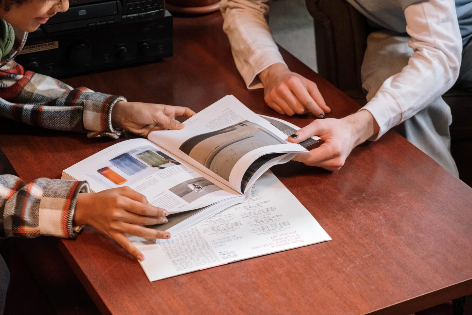 Two individuals reviewing a magazine on a wooden table indoors. Six Richest Rankings Mistakes Readers Make